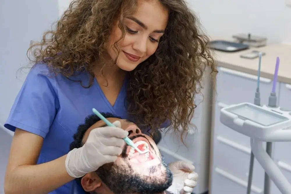 Dental professional performing a detailed oral examination using specialized lighting equipment to provide optimal patient care in modern treatment setting.