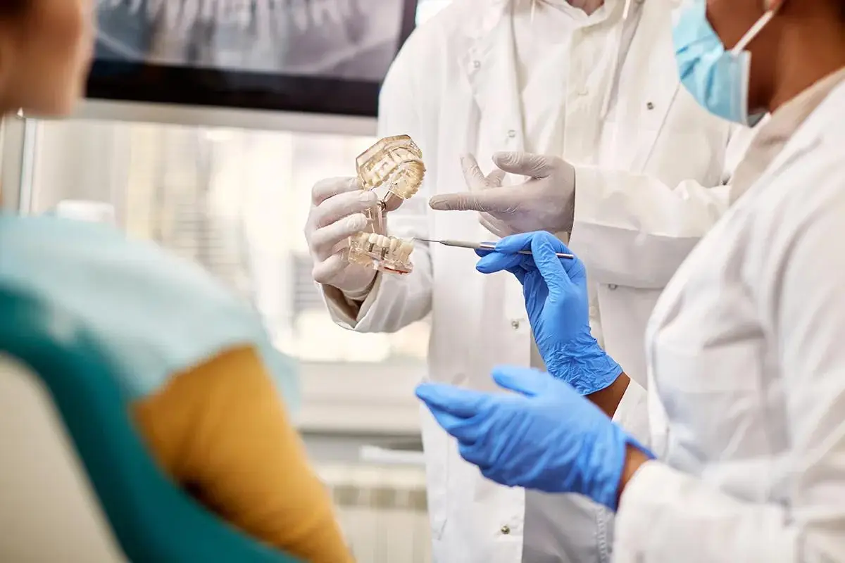 Dentists spending time demonstrating a dental implant model to the patient, highlighting prosthetic options and treatment planning in an educational consultation