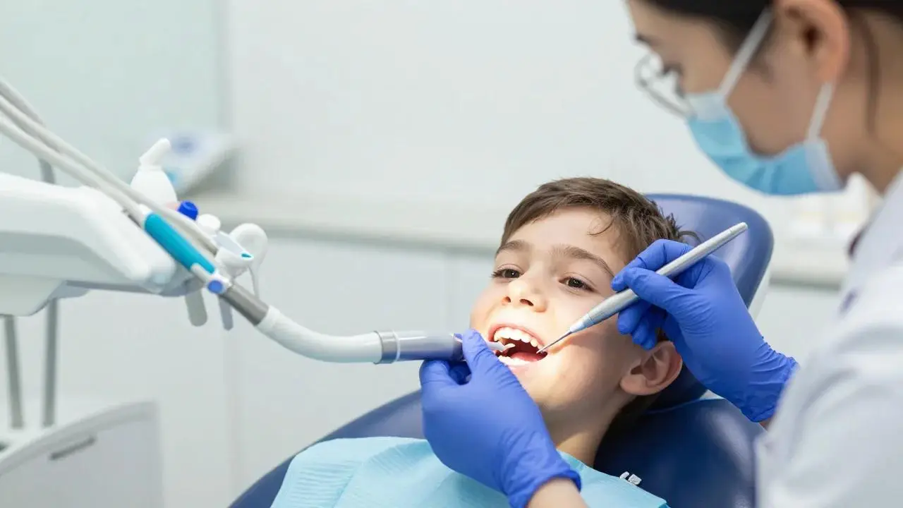 A smiling boy sits in a dental chair during a checkup