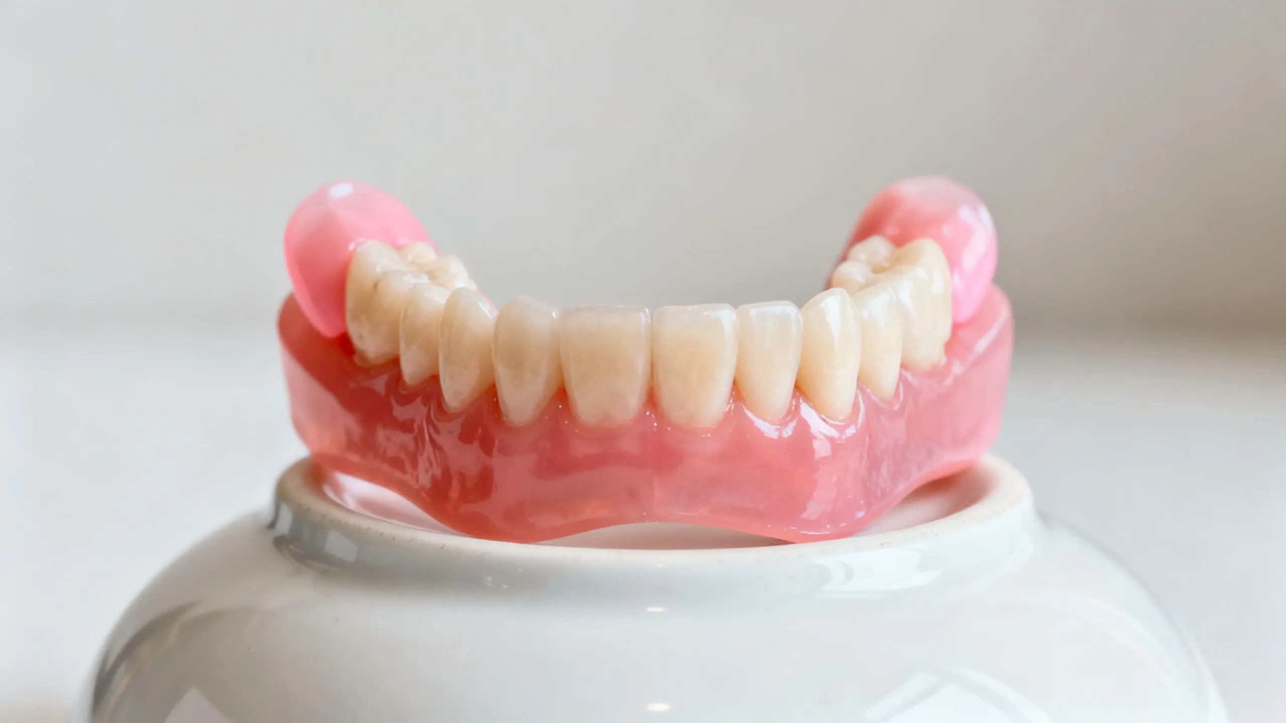 A full set of upper dentures resting on a white dish.