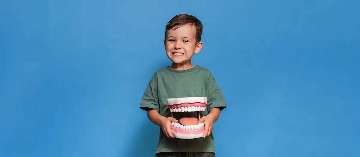 Child undergoes dental treatment with professional using instrument under light.